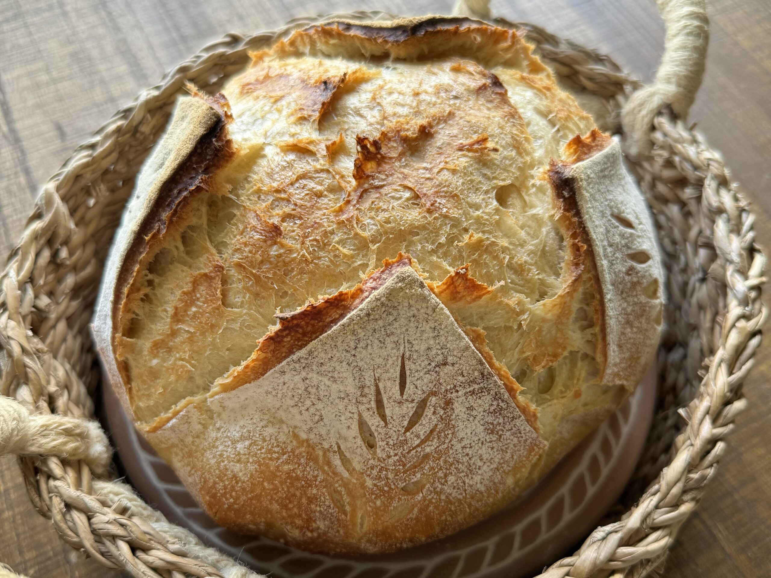 fresh artisan sourdough bread loaf in a basket on a wooden table