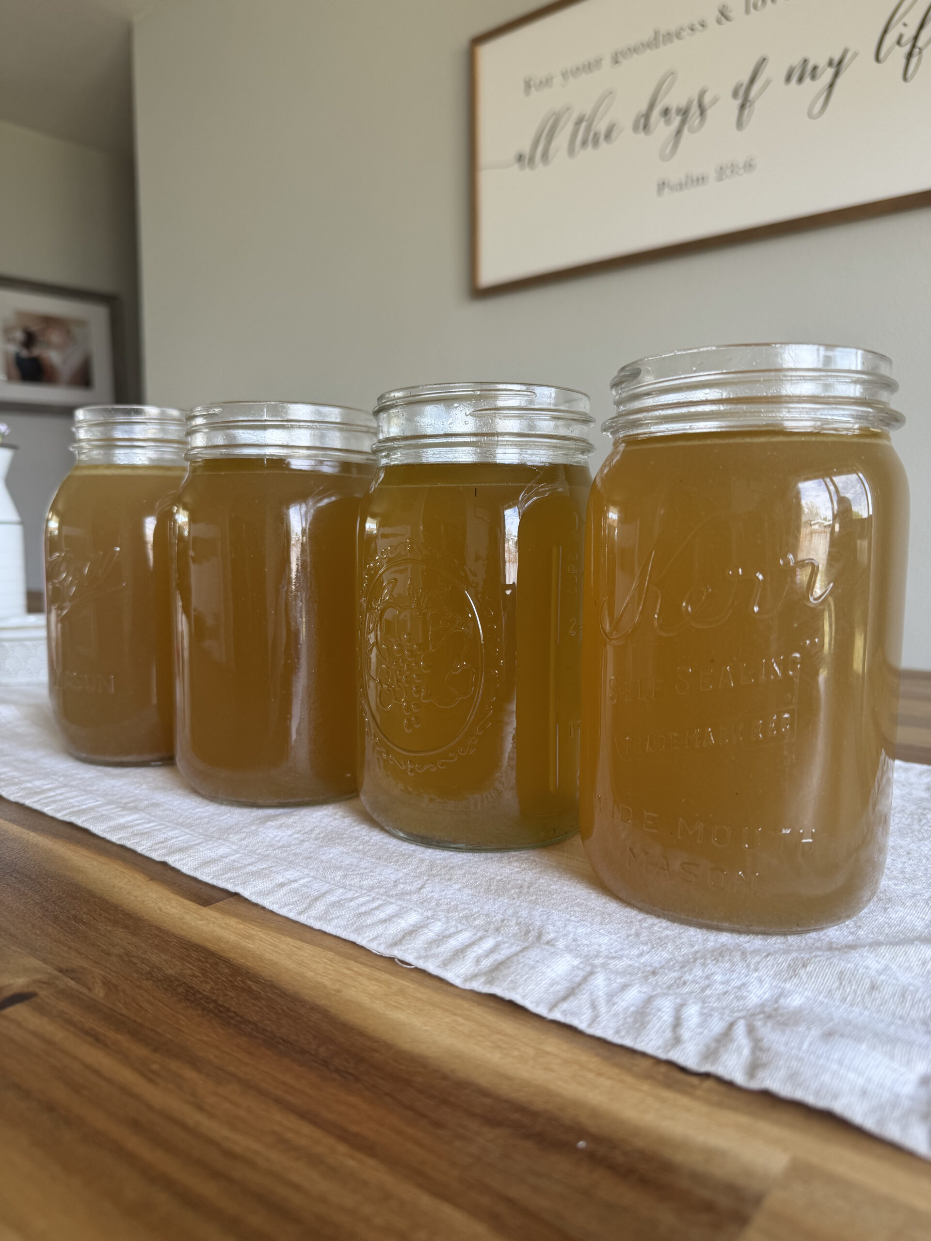 jars full of bone broth on a wooden kitchen table