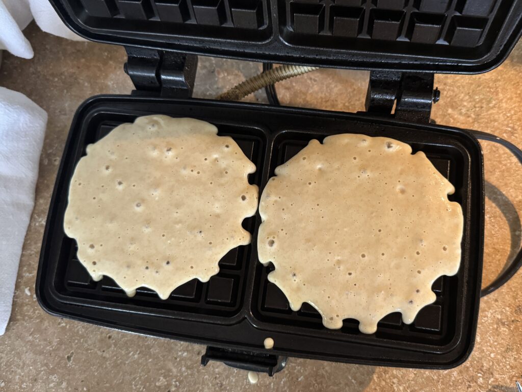 sourdough discard waffle batter poured into a waffle iron, on a countertop