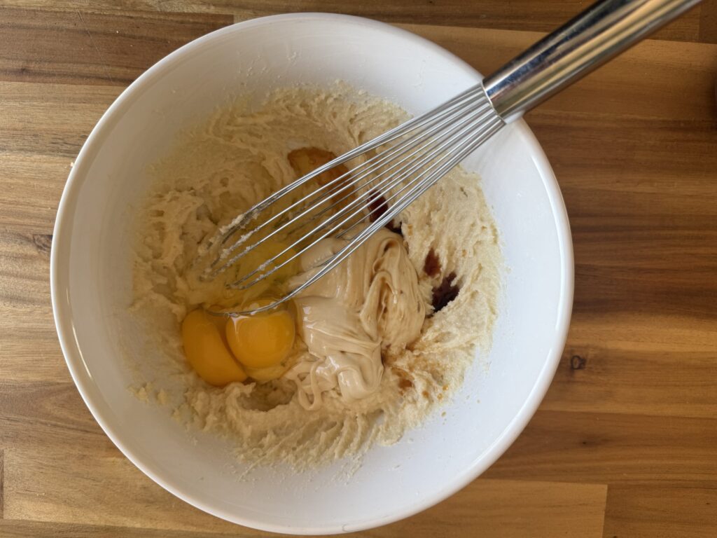 a white bowl on a wooden table with the wet ingredients in, ready to be mixed together
