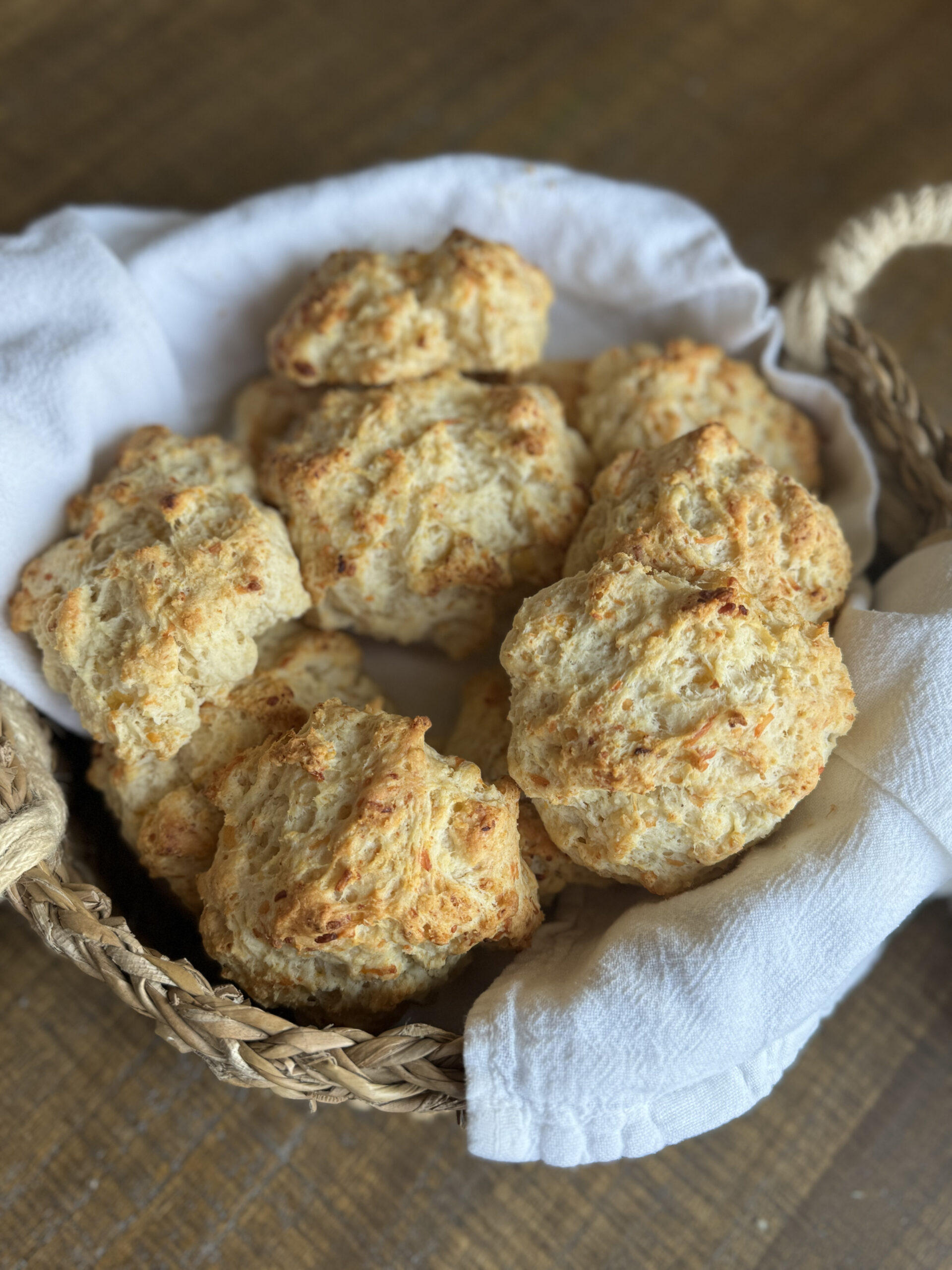 a linen lined basket filled with sourdough garlic cheddar biscuits